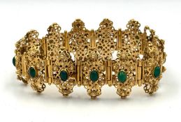 A fabulous Arabian gold and green stone ornate bracelet with filigree panels each set with a green