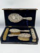 A cased hallmarked silver backed dressing table set with four brushes and a mirror by James Deakin &