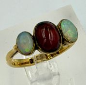 A 22ct gold three stone ring with central garnet and two opals, approximate weight 4.5g and size P