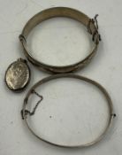 Two silver bangles together with a silver locket, various hallmarks