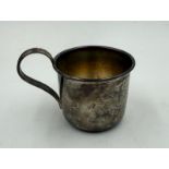 A silver christening cup or baby beaker with indistinct markings on the base