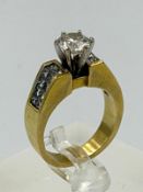 A single 1.25ct round brilliant diamond 18ct ring with channel set shoulders, two rows of ten