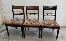 A set of three mahogany Georgian-style dining chairs on turned legs and with floral pattern seats