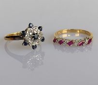 A sapphire and diamond cluster ring on a yellow gold setting and another yellow gold ring with ruby 