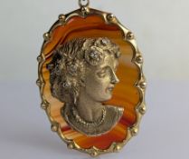 A yellow gold cast cameo pendant of a lady with diamond decoration to hair, applied to an onyx backg