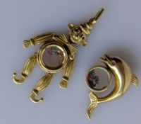 Two yellow gold pendants, a clown and dolphin with floating gems, both stamped and test for 14ct gol