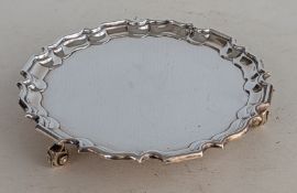 A George V silver salver with pie-crust border raised on three scrolled feet, hallmarked for Thomas 