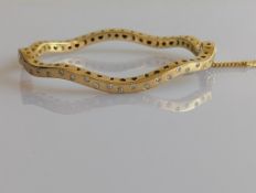 A yellow gold bangle with wavy design and diamond decoration, total diamond weight approximately 1.1