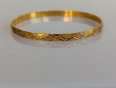 A yellow gold bangle with etched and textured lozenge decoration, 65mm, stamped 21ct, 14.3g