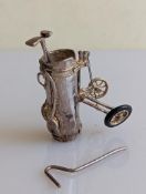 A silver golf caddy with two clubs, handle broken, on tyre missing, hallmarked for Douglas Pell Silv