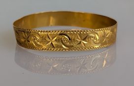 A yellow gold bangle with etched floral decoration, 65mm, stamped 21ct, 19g