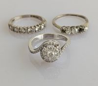 A diamond cluster crossover ring on a white gold setting decorated to the shoulders, central diamond