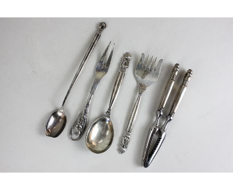 Five Georg Jenson items of silver, to include a pair of nutcrackers, serving fork and spoon and a long handled spoon (bowl wo
