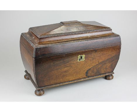 A 19th century rosewood tea caddy of bombe shaped sarcophagus form with gadroon border, on turned bun feet, enclosing a pair 