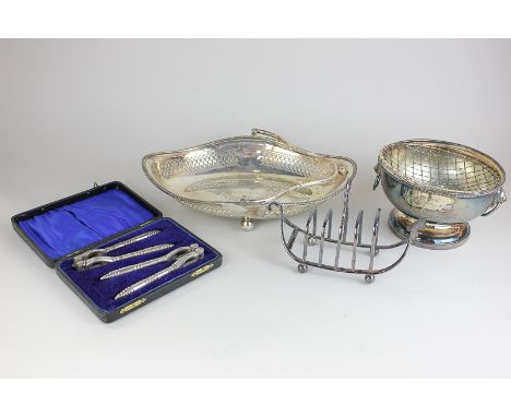 A silver plated toast rack, a silver plated cake basket with pierced detail, a pair of cased nutcrackers and a presented pede