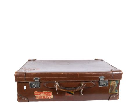 A Vintage leather-covered cardboard suitcase, with several travel labels, the chrome plate locks impressed with the Isle of M