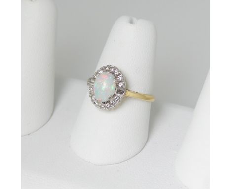 An opal and diamond Ring, the central oval cabochon opal approx 8.25mm x 6.1mm claw set above a surround to a baguette diamon