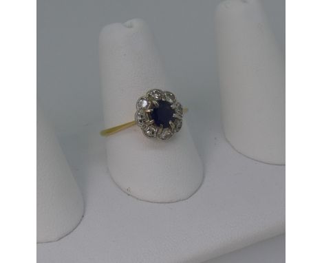 A sapphire and diamond cluster Ring, the circular facetted sapphire, 5.7mm diameter, claw set above a surround of eight small