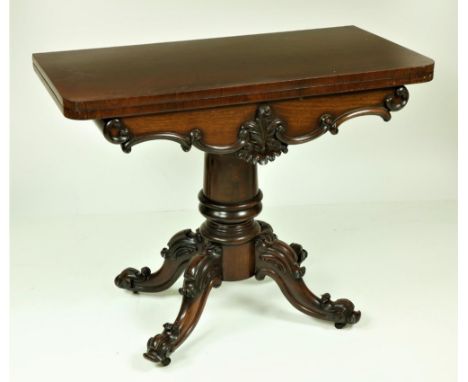 A Victorian fold-over rosewood Card Table, with shaped C scroll and leaf carved frieze on a heavy turned stem with ornate qua