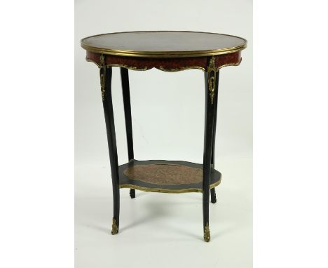 An elegant oval shaped two tier Table, the rosewood top with ormolu rim over a frieze with ornate mounts united by a shelf wi