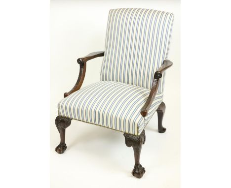 An attractive George II style Library Armchair, with padded back and seat, the arm rests with fish scale fronts and raised on