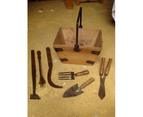 A selection of old gardening tools in a wooden basket. 