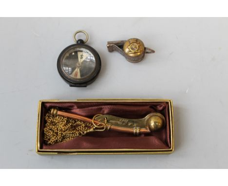A MILITARY STYLE MARCHING TYPE COMPASS, dated 1906, a royal Artillery button whistle and a 'RNVR' bosun's whistle (3) Buyers 