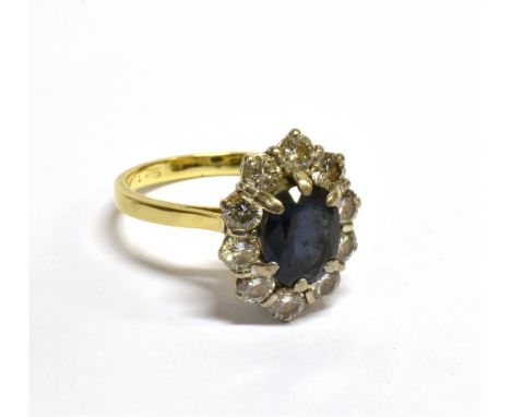 A VINTAGE CONTINENTAL 18CT GOLD, SAPPHIRE AND DIAMOND OVAL CLUSTER RING centred with an oval mixed-cut very dark-blue/black s