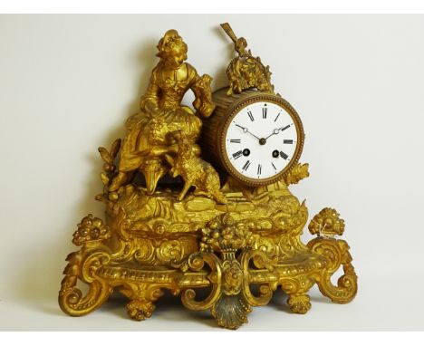 Late 19th century gilt metal mantel clock, seated maiden with dog, decorated with floral swags and fruit baskets. circular en