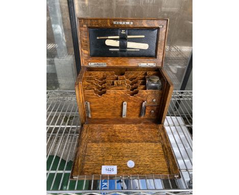 A VINTAGE OAK FOLDING WRITING BOX WITH INK WELL AND LEATHER PAD