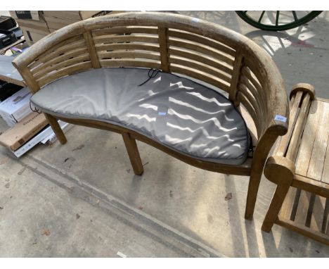 A TEAK SLATTED CURVED GARDEN BENCH WITH CUSHION