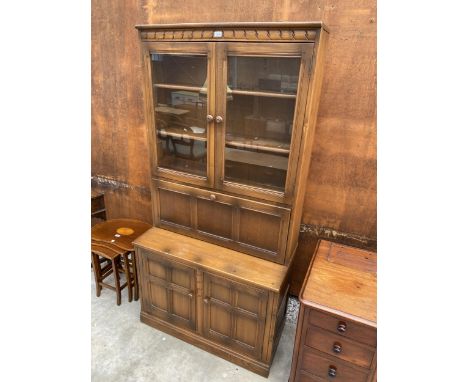 AN ERCOL ELM TWO DOOR GLAZED TWO DOOR BOOKCASE WITH DROP DOWN SECTION, 38.5" WIDE