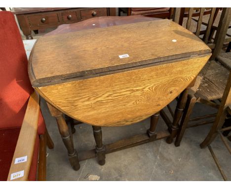 AN OVAL OAK GATE LEG TABLE ON TURNED LEGS, 40.5" X 29.5" OPENED