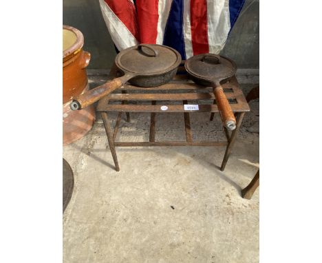 A VINTAGE METAL TRIVET STAND AND TWO VINTAGE CAST IRON PANS WITH WOODEN HANDLES