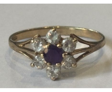A MARKED 9 CARAT GOLD RING WITH CENTRE RUBY SURROUNDED BY SIX CUBIC ZIRCONIAS IN A FLOWER DESIGN SIZE O