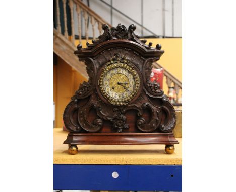 AN ORNATELY CARVED MAHOGANY MANTLE CLOCK