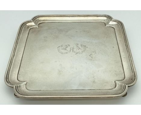 An Art Deco square shaped silver salver raised on 4 feet with stepped design to rim. Engraved to centre with the family crest