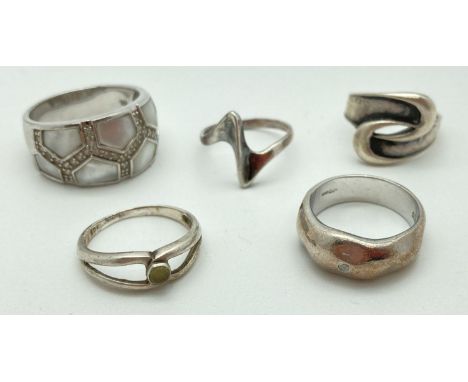 A collection of 5 silver dress rings in varying styles and sizes. To include band ring set with a single clear stone, band ri