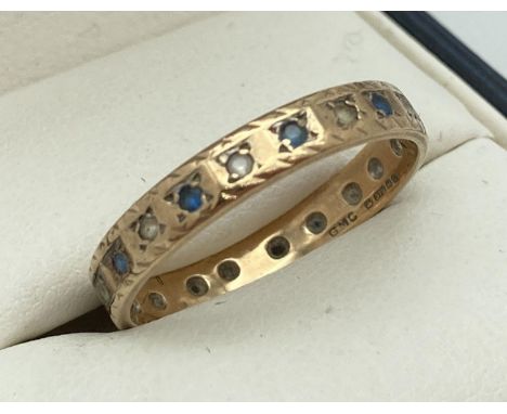 A vintage 9ct gold full eternity ring set with blue and clear stones (one missing). Full hallmarks to inside of band. Ring si