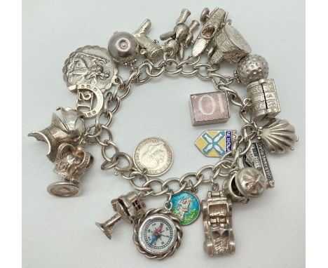 A vintage silver charm bracelet with 21 silver and white metal charms. Many charms open to reveal characters or items inside.