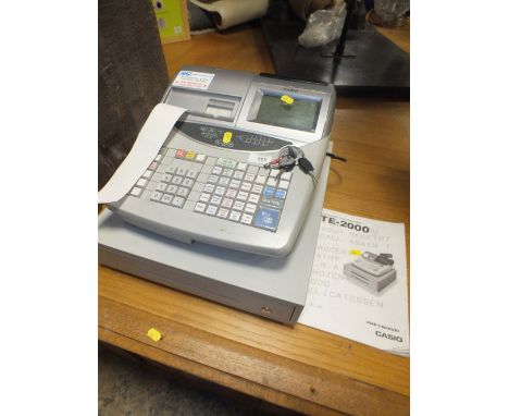 A CASIO CASH REGISTER WITH KEYS AND MANUAL