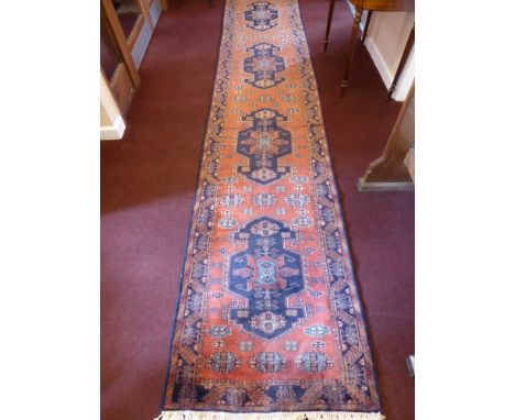 A 20th Century Iranian Wool Runner, navy blue on pink ground with four central gül, approx 415 x 82 cms.