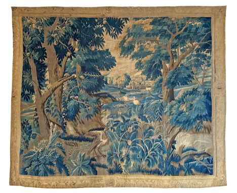 A large antique European handwoven pastoral needlework tapestry depicting a woodland scene with lush foliage, trees, and bird