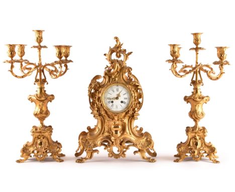 An antique French gilt bronze Rococo style clock garniture,&nbsp;the mantel clock of waisted keyhole shape, profusely decorat