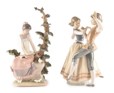 A pair of Lladró figures to include a dancing couple and a woman sitting on a bench underneath a tree, tallest 32cm. (2)