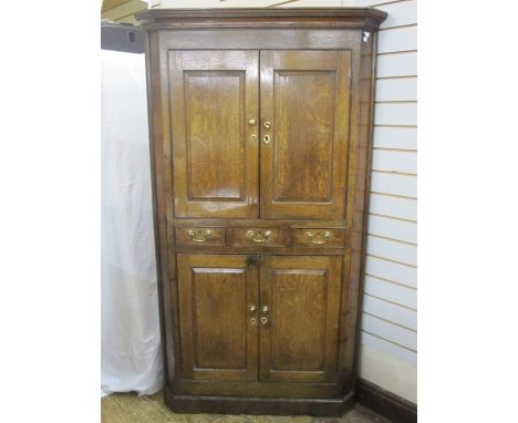 18th century oak floor standing corner cupboard with cavetto cornice, upper section enclosed by pair fielded panel doors, thr