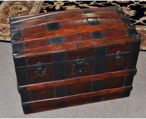 An early 20th century metal bound dome topped wooden trunk, the hinged cover enclosing later tray, width 71cm, depth 42cm, he