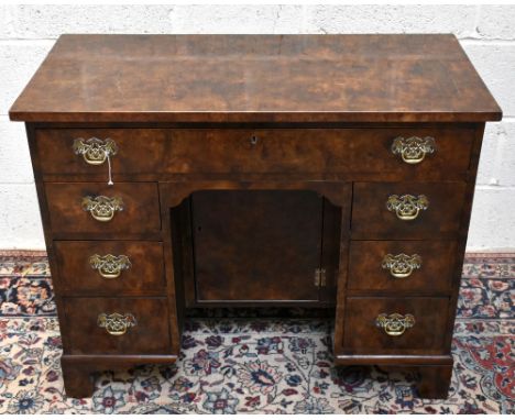 A George III style walnut knee-hole desk, with an arrangement of seven drawers, on bracket feet, height 77cm, width 96cm, dep