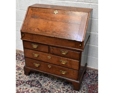 An 18th century oak two section bureau, with fall enclosing a fitted interior, above two short and two long drawers, on brack