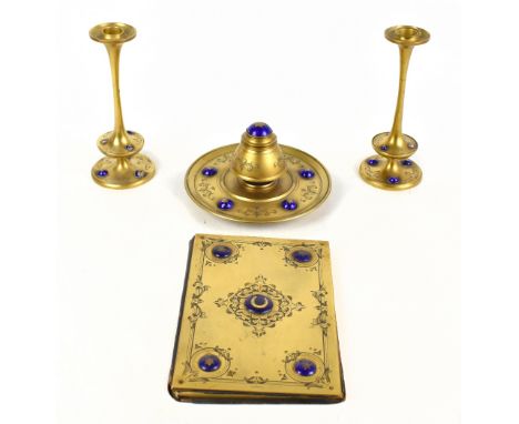 A 19th century four piece gilt brass desk set comprising inkwell, blotter of rectangular form, a pair of candlesticks, each w